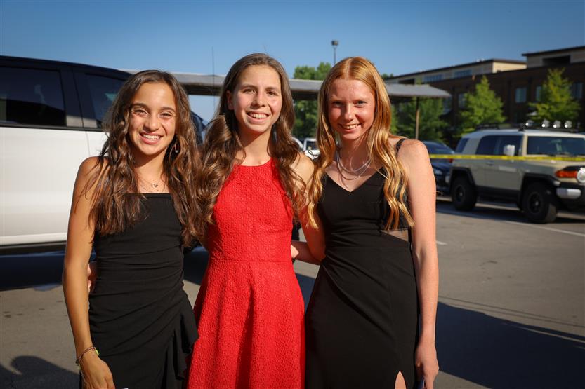 Three young women stand together and smile